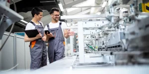 Dwoje inżynierów rozmawia w fabryce na temat obserwacji hali produkcyjnej metodą gemba walk